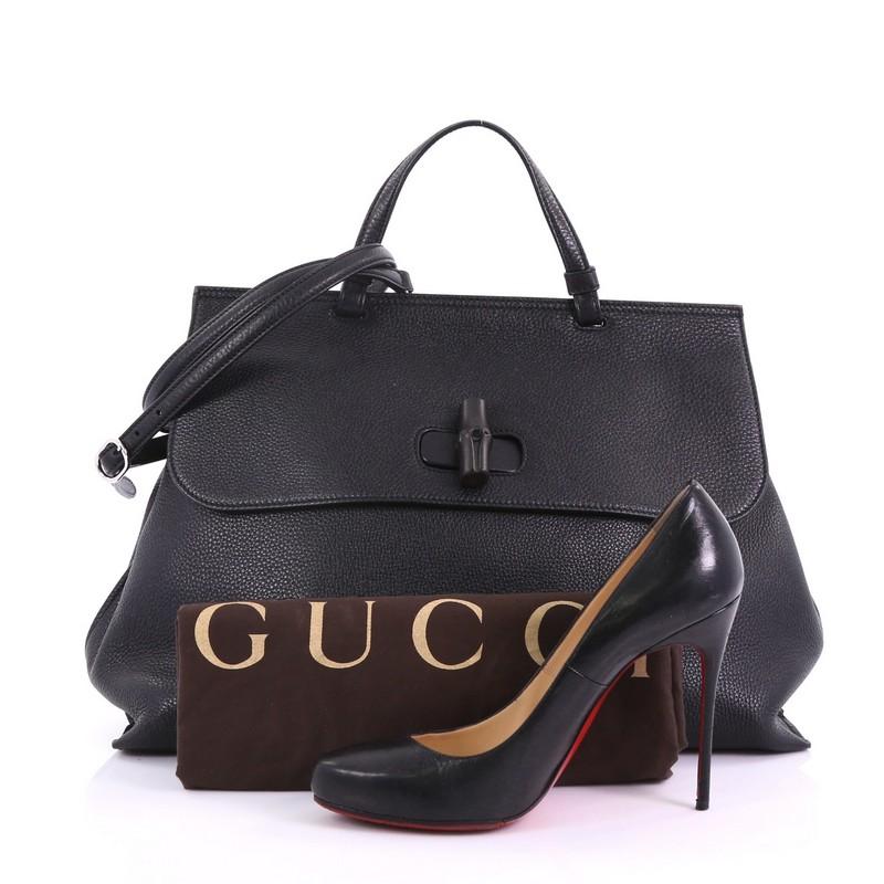 This Gucci Bamboo Daily Top Handle Bag Leather Large, crafted from black leather, features flat top handle, and silver-tone hardware. Its flap with bamboo turn-lock closure opens to a pink fabric interior with zip and slip pockets. **Note: Shoe
