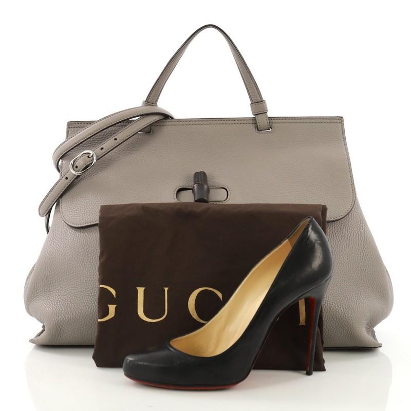 This Gucci Bamboo Daily Top Handle Bag Leather Large, crafted from gray leather, features a flat top handle, flap turn-lock closure with dark lacquered bamboo detail, and silver-tone hardware. It opens to a multicolor fabric interior with zip and