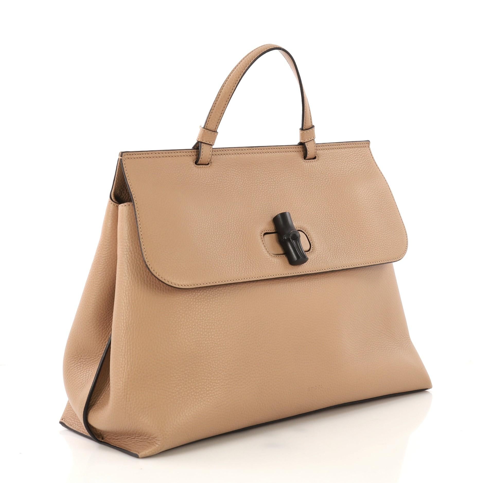 This Gucci Bamboo Daily Top Handle Bag Leather Large, crafted from beige leather, features flat top handle and silver-tone hardware. Its flap with bamboo turn-lock closure opens to a multicolor printed fabric interior with zip and slip pockets.