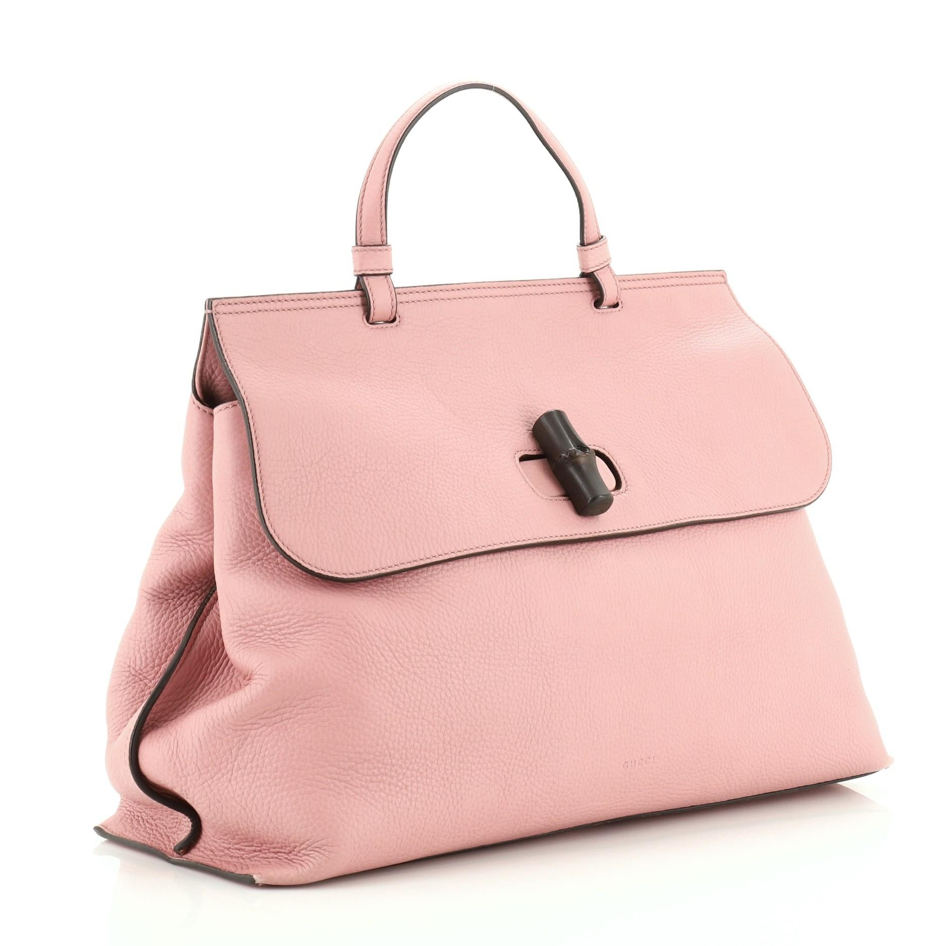 This Gucci Bamboo Daily Top Handle Bag Leather Large, crafted from pink leather, features a flat top handle and silver-tone hardware. Its flap with bamboo turn-lock closure opens to a purple and yellow printed fabric interior with zip and slip