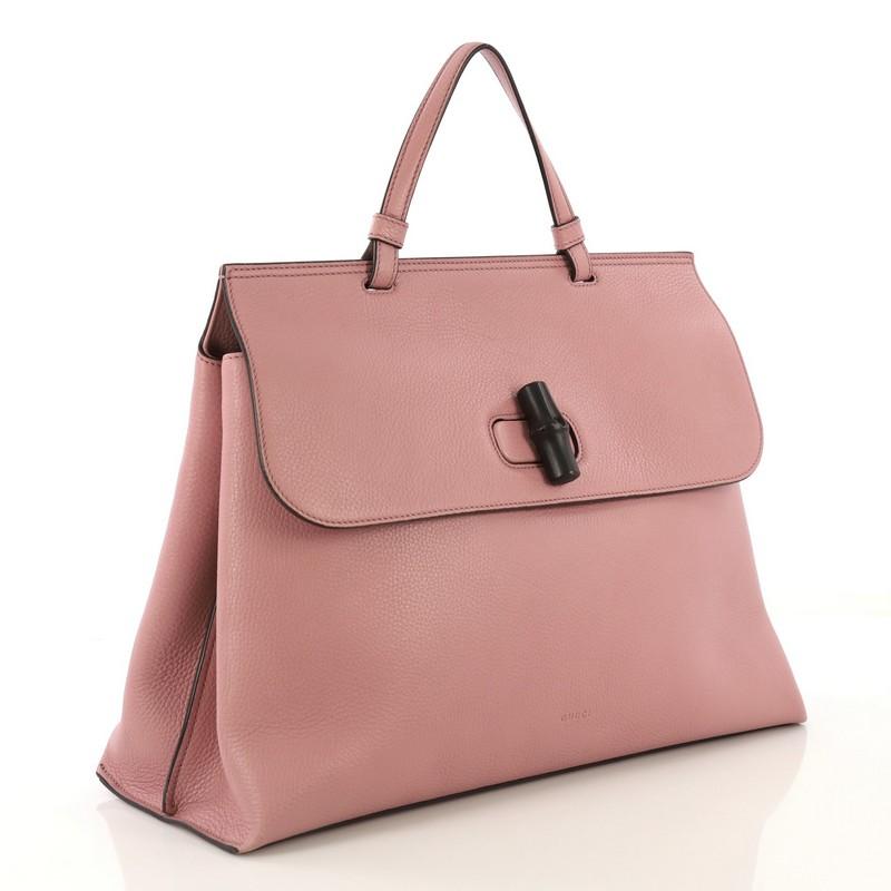 This Gucci Bamboo Daily Top Handle Bag Leather Large, crafted from pink leather, features a flat top handle and silver-tone hardware. Its flap with bamboo turn-lock closure opens to a multicolor fabric interior with zip and slip pockets. 

Estimated