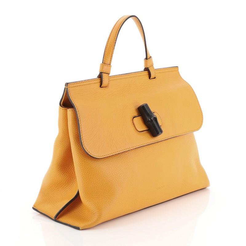 This Gucci Bamboo Daily Top Handle Bag Leather Medium, crafted from yellow leather, features a flat top handle and silver-tone hardware. Its flap with bamboo turn-lock closure opens to a printed fabric interior with slip pockets. 

Estimated Retail