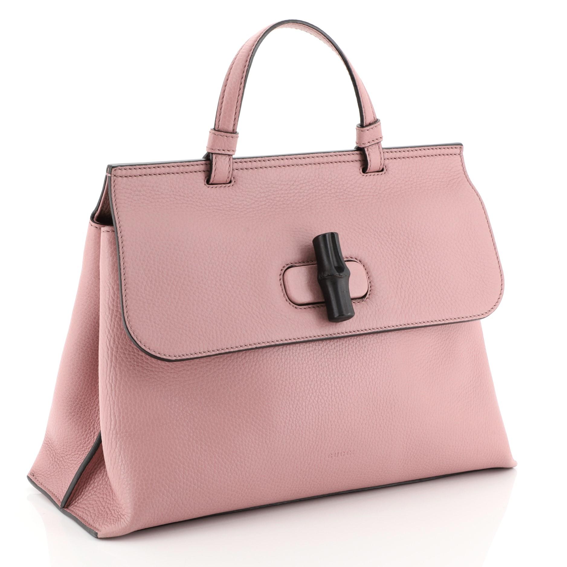 This Gucci Bamboo Daily Top Handle Bag Leather Medium, crafted from pink leather, features a flat top handle and silver-tone hardware. Its flap with bamboo turn-lock closure opens to a neutral multicolor printed fabric interior with zip and slip