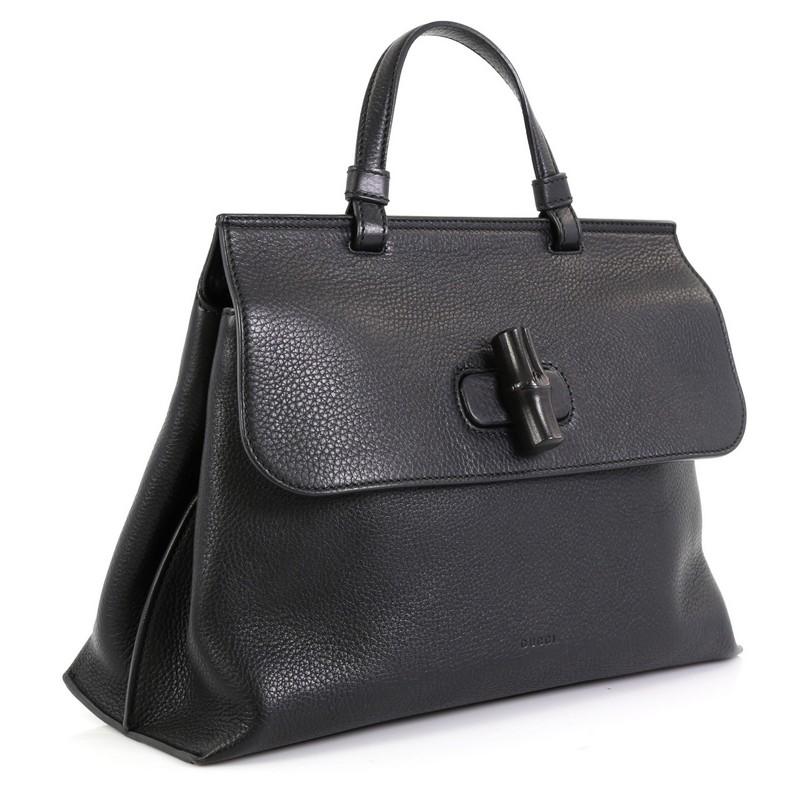 This Gucci Bamboo Daily Top Handle Bag Leather Medium, crafted from black leather, features a flat top handle and silver-tone hardware. Its flap with bamboo turn-lock closure opens to a neutral fabric interior with slip pockets. 

Estimated Retail