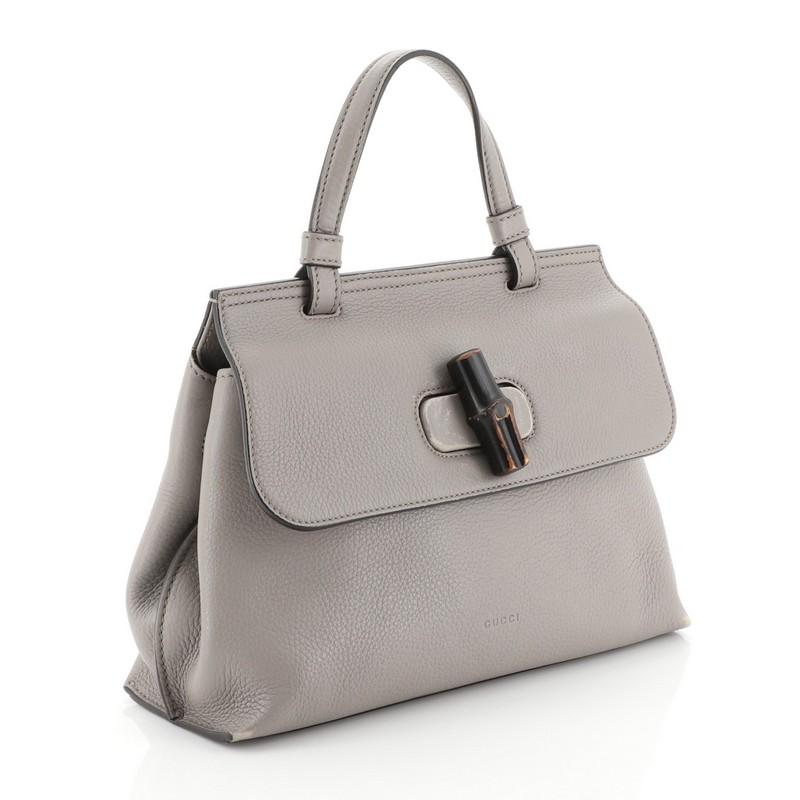 This Gucci Bamboo Daily Top Handle Bag Leather Small, crafted from gray leather, features a flat top handle and silver-tone hardware. Its flap with bamboo turn-lock closure opens to a pink and multicolor fabric interior with zip and slip