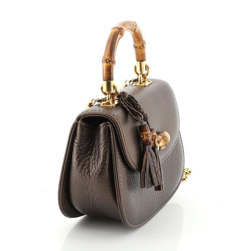 This Gucci Bamboo Night Handbag Leather Mini, crafted from brown leather, features a looped bamboo top handle, bamboo turn-lock closure, braided leather bow with bamboo and tassel detail, and gold-tone hardware. Its turn-lock closure opens to a