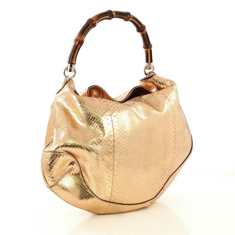This Gucci Bamboo Peggy Hobo Python Large, crafted in genuine rose gold Python skin, features looping bamboo handle, and gold-tone hardware. Its fold-over flap top opens to a beige fabric interior with zip and slip pockets. This item can only be