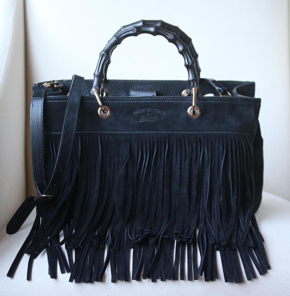 Gucci's Italian-made suede bag features the brand's signature bamboo handle along the top, extra long fringing and tassels. Black suede (Calf). Adjustable shoulder strap. Bamboo handles, fringed suede trim, designer stamp, silver-tone hardware. Two