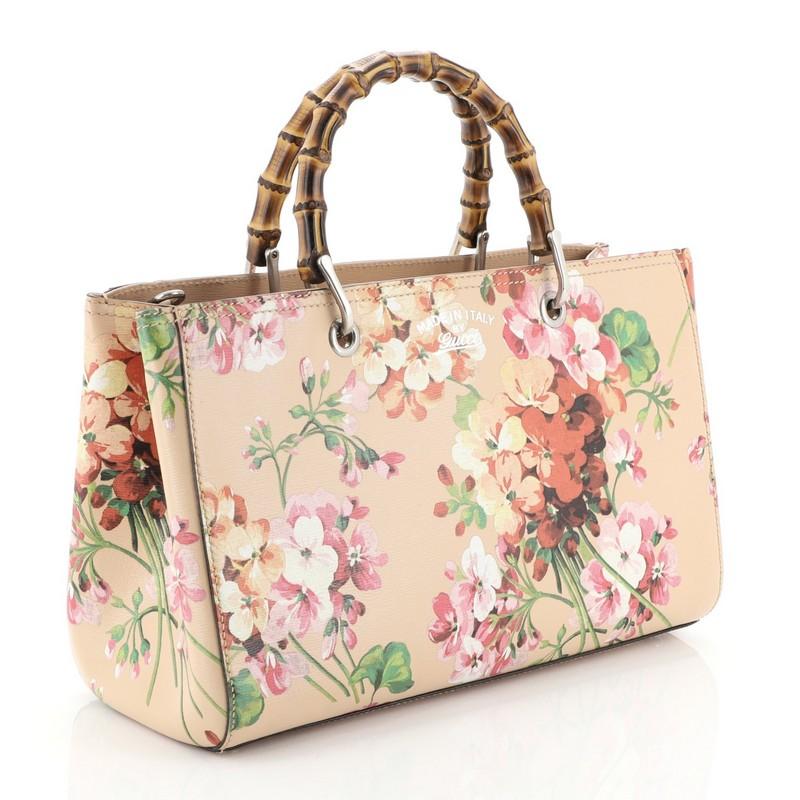 This Gucci Bamboo Shopper Tote Blooms Print Leather Medium, crafted from neutral blooms print leather, features bamboo top handles, protective base studs, stamped logo at the front, and aged silver-tone hardware. Its hidden magnetic snap closure