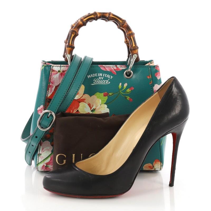 This Gucci Bamboo Shopper Tote Blooms Print Leather Mini, crafted from teal Blooms print leather, features Gucci's signature sturdy bamboo handles, stamped logo at the front, and bamboo and aged silver-tone hardware. Its hidden magnetic snap closure