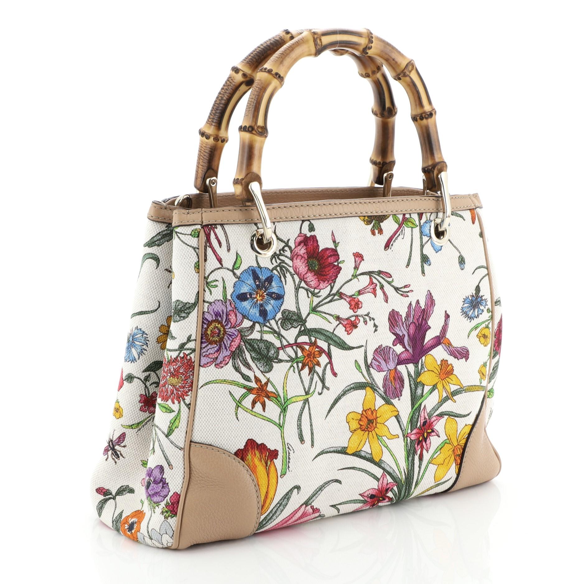 This Gucci Bamboo Shopper Tote Flora Canvas Small, crafted in neutral printed canvas, features dual bamboo handles and gold-tone hardware. Its hidden magnetic snap closure opens to a neutral fabric interior divided into two compartments with side