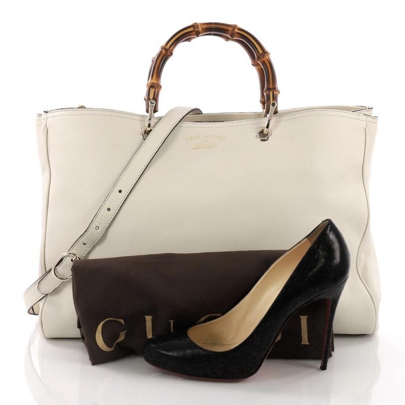 This Gucci Bamboo Shopper Tote Leather Large, crafted from off-white leather, features sturdy bamboo handles, stamped logo at the front, and gold-tone hardware. Its hidden magnetic snap closure opens to a beige fabric interior with middle zip and