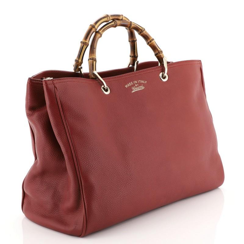 This Gucci Bamboo Shopper Tote Leather Large, crafted from red leather, features bamboo top handles, stamped logo at the front and gold-tone hardware. Its hidden magnetic snap closure opens to a neutral fabric interior with middle zip compartment