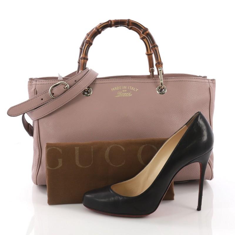 This Gucci Bamboo Shopper Tote Leather Medium, crafted from mauve leather, features Gucci's signature sturdy bamboo handles, stamped logo at the front, and gold-tone hardware. Its magnetic snap closure opens to a beige fabric interior with middle