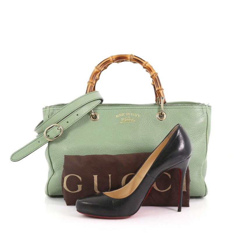 This Gucci Bamboo Shopper Tote Leather Medium, crafted in green leather, features sturdy bamboo handles, protective base studs, and gold-tone hardware. Its hidden magnetic snap closure opens to a beige fabric interior divided into two compartments