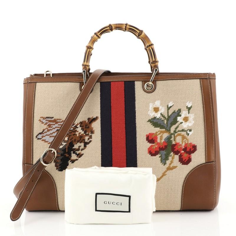 This Gucci Bamboo Shopper Tote Needle Point Textile Large, crafted from brown needle point textile and brown leather, features bamboo handles, embroidered floral on front, bee and cherries with web stripe on the back, protective base studs, and