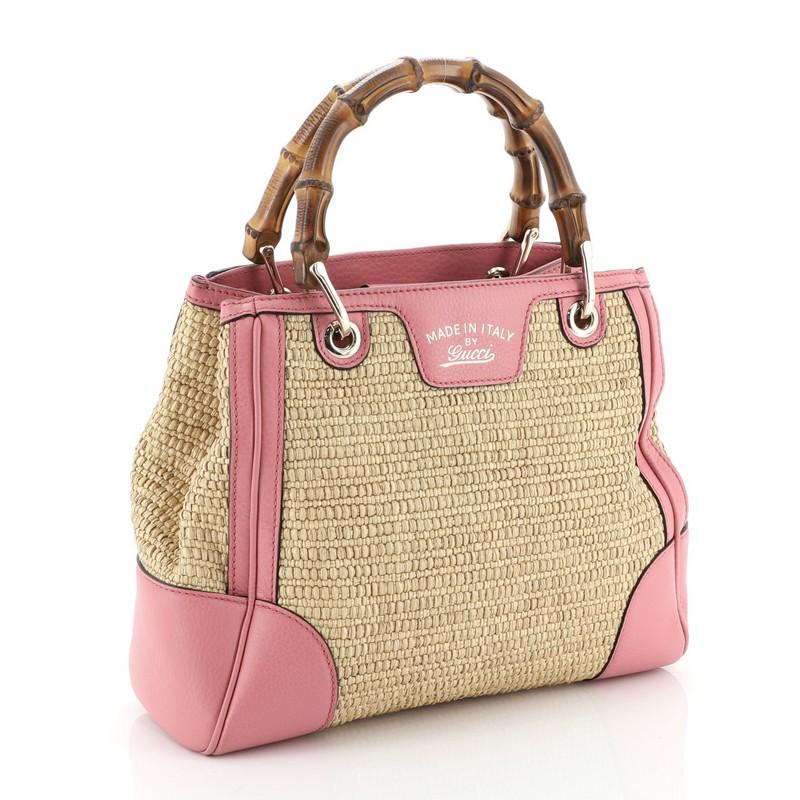 This Gucci Bamboo Shopper Tote Straw Small, crafted from neutral straw and pink leather, features bamboo handles, protective base studs, and gold-tone hardware. Its magnetic tab closure opens to a neutral multicolor printed fabric interior divided