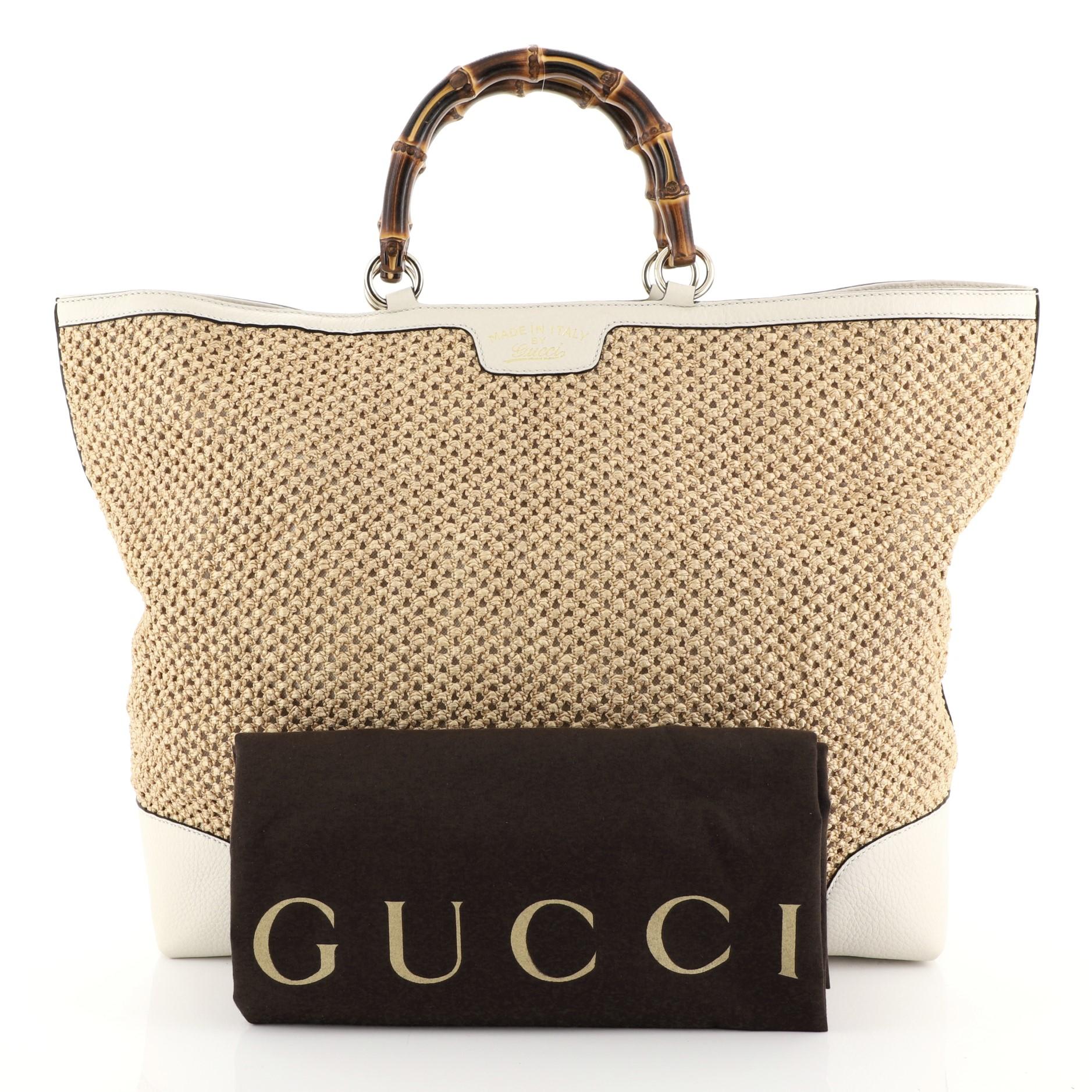 This Gucci Bamboo Shopper Tote Woven Straw Large, crafted from neutral woven straw and off-white leather, features Gucci's signature sturdy bamboo handles, and gold-tone hardware. Its hook closure opens to a neutral fabric interior with side zip and
