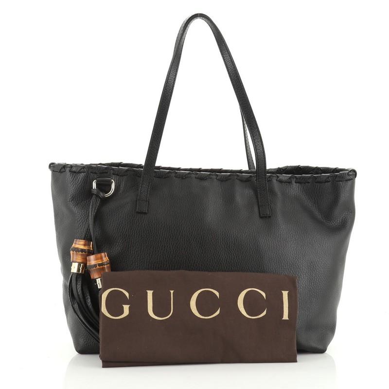 This Gucci Bamboo Tassel Tote Leather Large, crafted in black leather, features dual flat leather handles, whipstitched detailing and gold-tone hardware. Its magnetic closure opens to a black fabric interior slip pockets.

Estimated Retail Price: