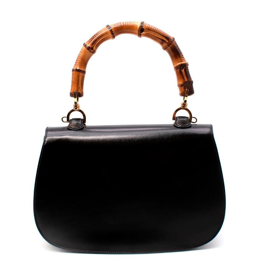 Gucci Bamboo Top Handle Black Leather Bag
 

 - Vintage inspired, oval shaped smooth black leather bag, featuring the Brand's signature bamboo curved top handle, and twist lock closure
 - Flap front
 - One internal compartment, lined in Hibiscus red
