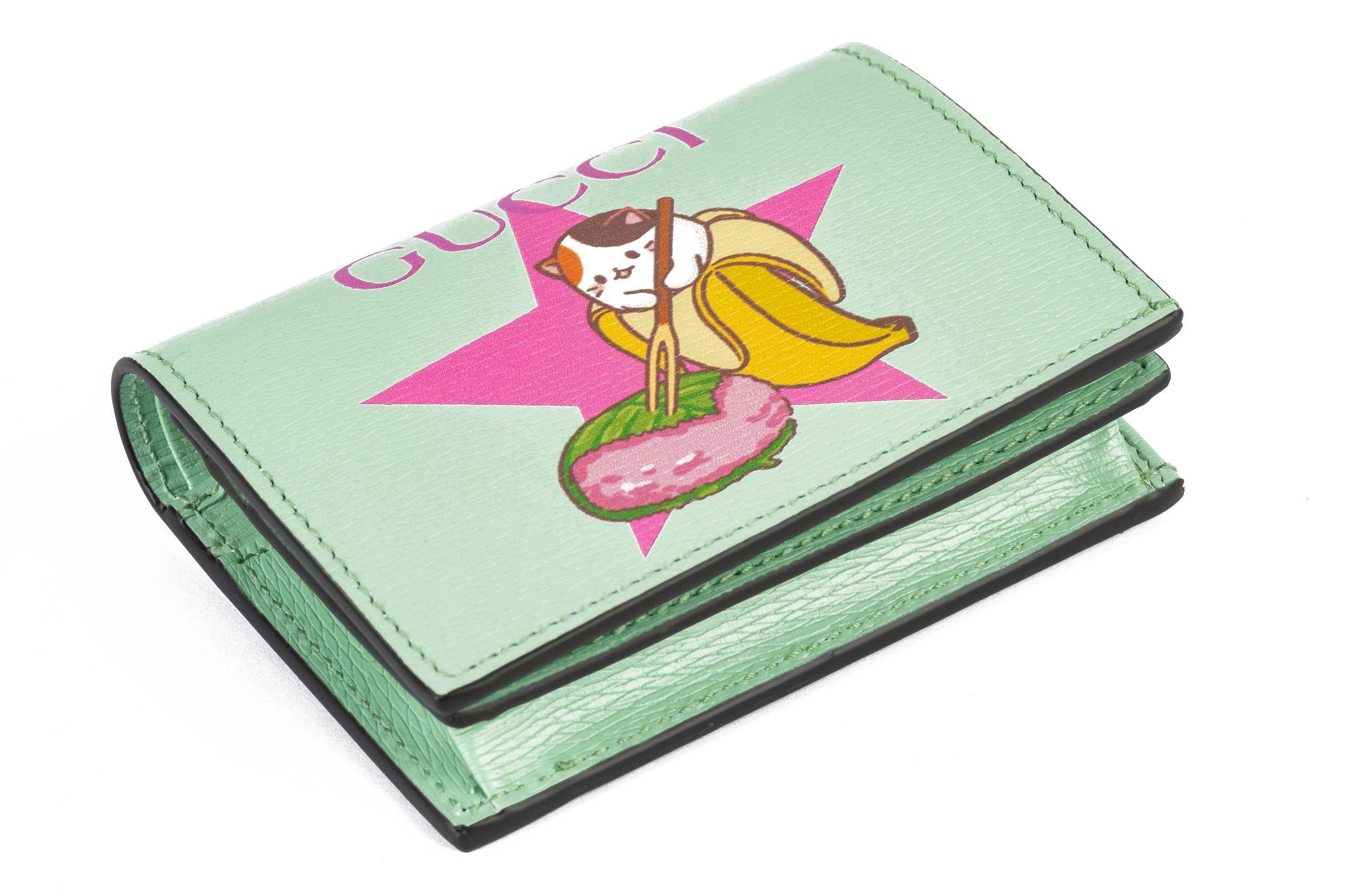 Ce portefeuille bifold Gucci Bananya en édition limitée est disponible en vert menthe avec des accessoires dorés. Fermeture par bouton-pression, cinq fentes pour cartes de crédit, compartiment à billets latéral et compartiment à monnaie zippé. Livré
