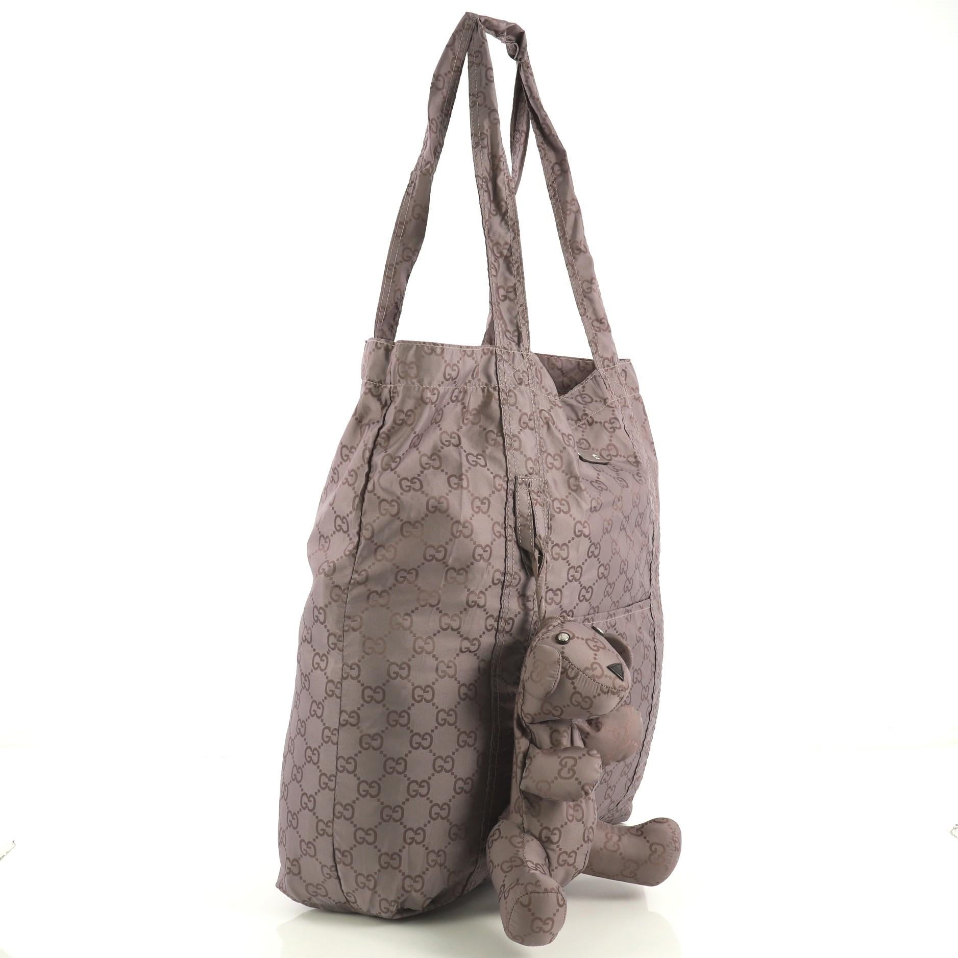 This Gucci Bear Charm Tote Guccissima Nylon Large, crafted from neutral guccissima nylon, features dual flat handles, bear charm, and silver-tone hardware. It opens to a neutral nylon interior. 

Estimated Retail Price: $825
Condition: Excellent.