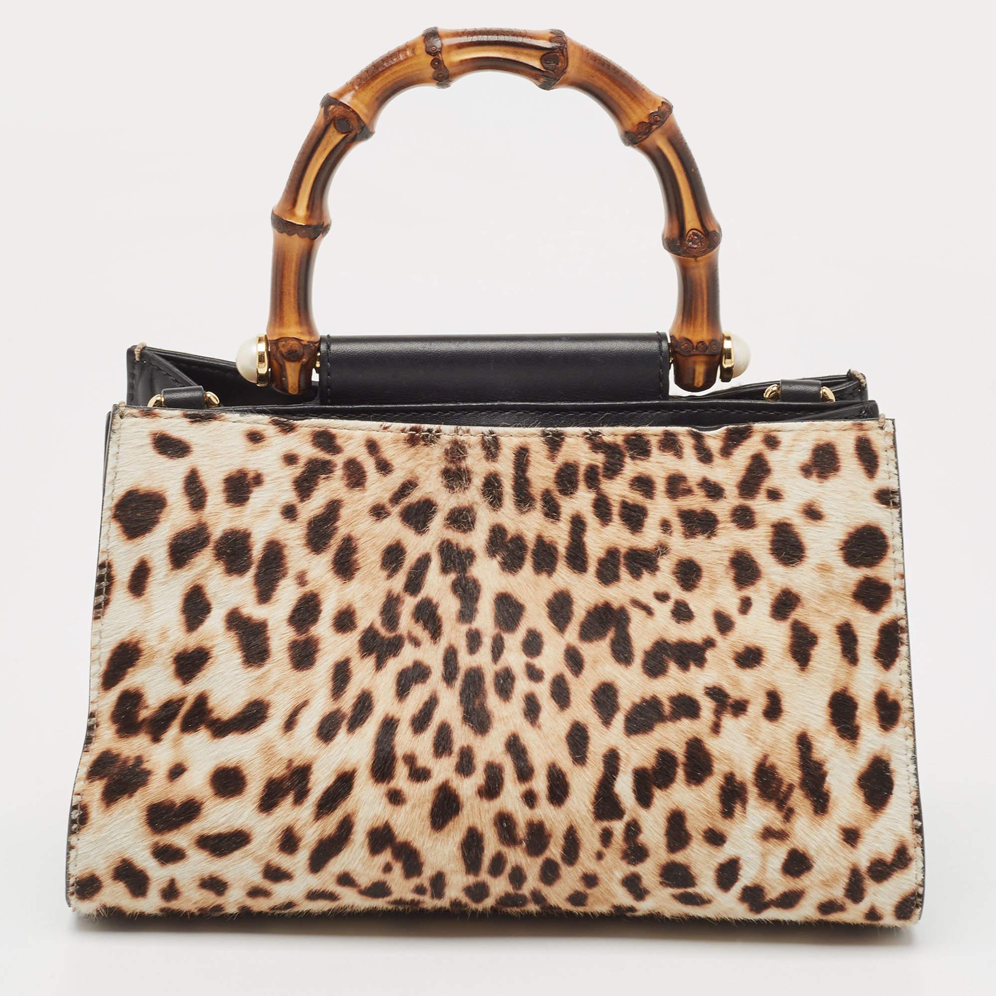 This Gucci Nymphaea bag is characterized by recognizable bamboo handles and an elegant silhouette. Crafted in smooth, black leather and leopard-printed calfhair, this bag boasts a spacious interior lined with suede. A stunning creation you deserve