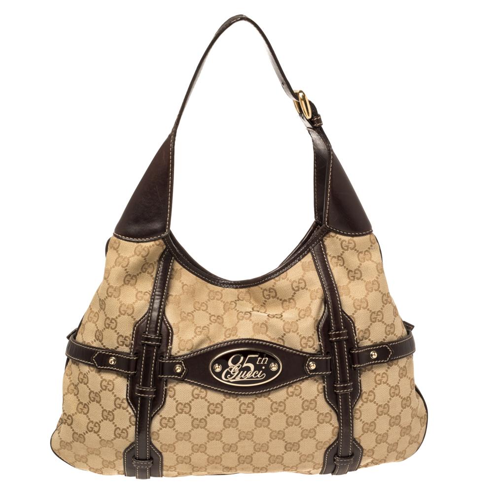 This Gucci hobo is crafted from GG canvas and leather and features dual flat leather handles, a logo plate commemorating Gucci's 85th anniversary on the rear side, and oversized Horsebit detailing in gold-tone at the front. Its zip closure opens to
