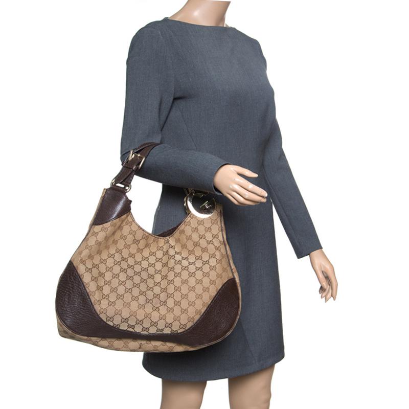 The Gucci Charlotte hobo is all that you need for a day of shopping and running errands in style. It is crafted from beige GG coated canvas and brown leather trims. This bag has two brown flat handles which are attached to the bag through a