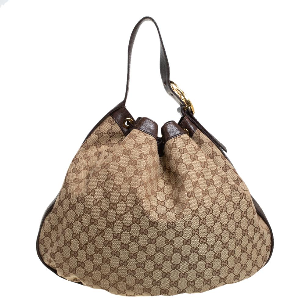 This stylish hobo bag by Gucci is great for everyday use. Crafted from the brand's signature GG canvas and leather, it comes in lovely brown & beige hues. It is styled with a single handle adorned with the iconic interlocking logo, a drawstring