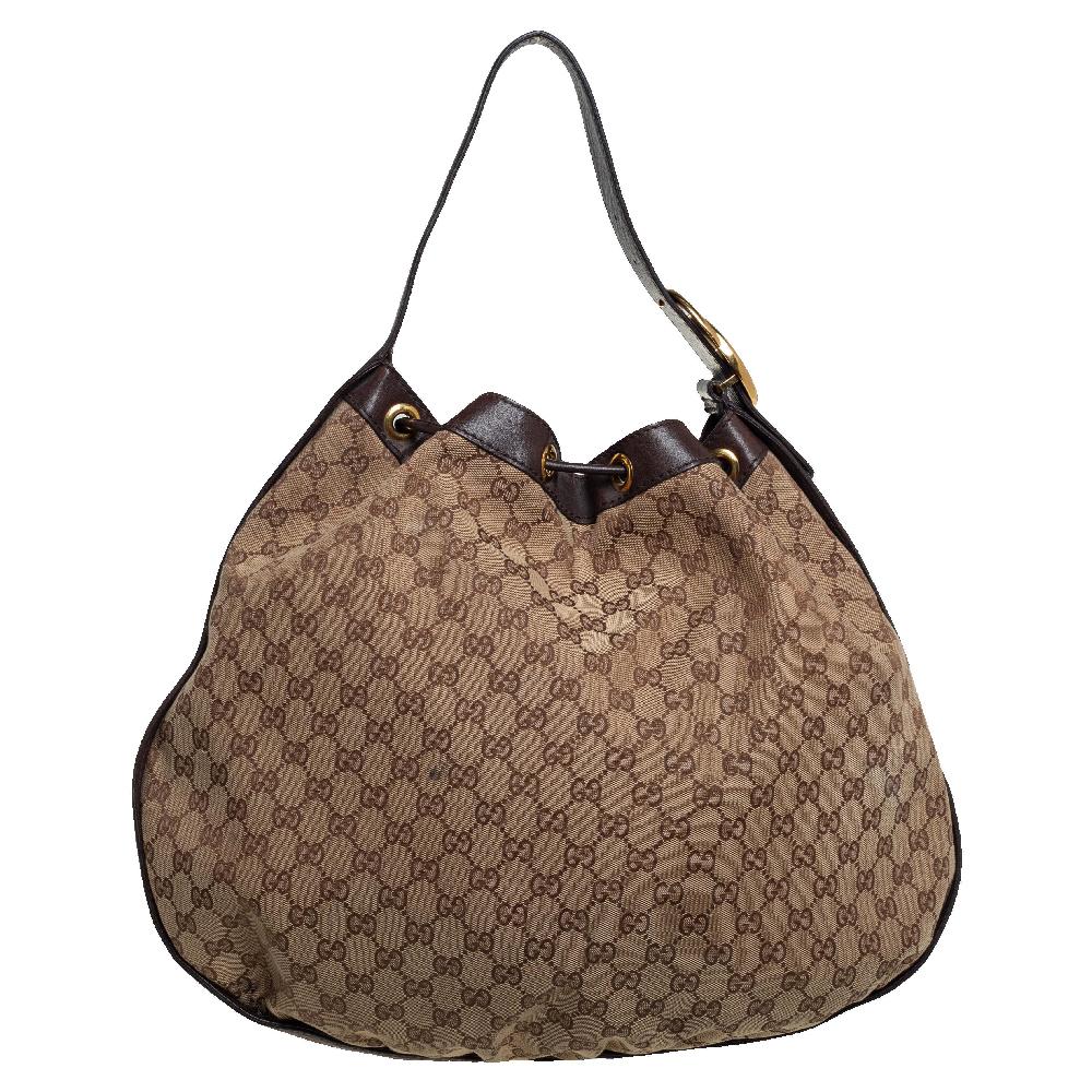 This stylish hobo bag by Gucci is great for everyday use. Crafted from the brand's signature GG canvas and leather, it comes in lovely brown & beige hues. It is styled with a single handle adorned with the iconic interlocking logo, a drawstring