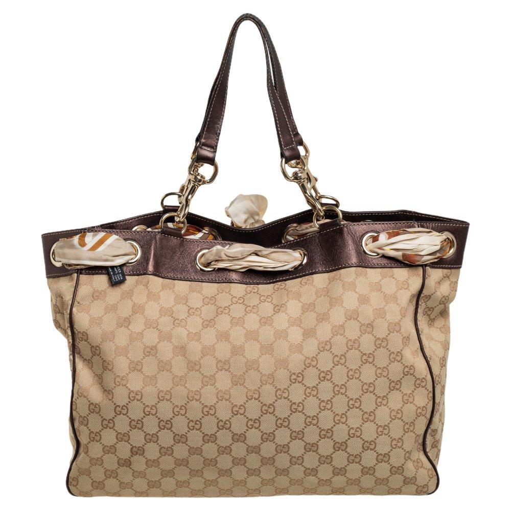 Made by Gucci, this Positano tote is a perfect balance of elegance and practical utility. Crafted from GG canvas and leather, it is adorned with a Gucci scarf interlaced at the top. The bag is equipped with a capacious interior and suspends from