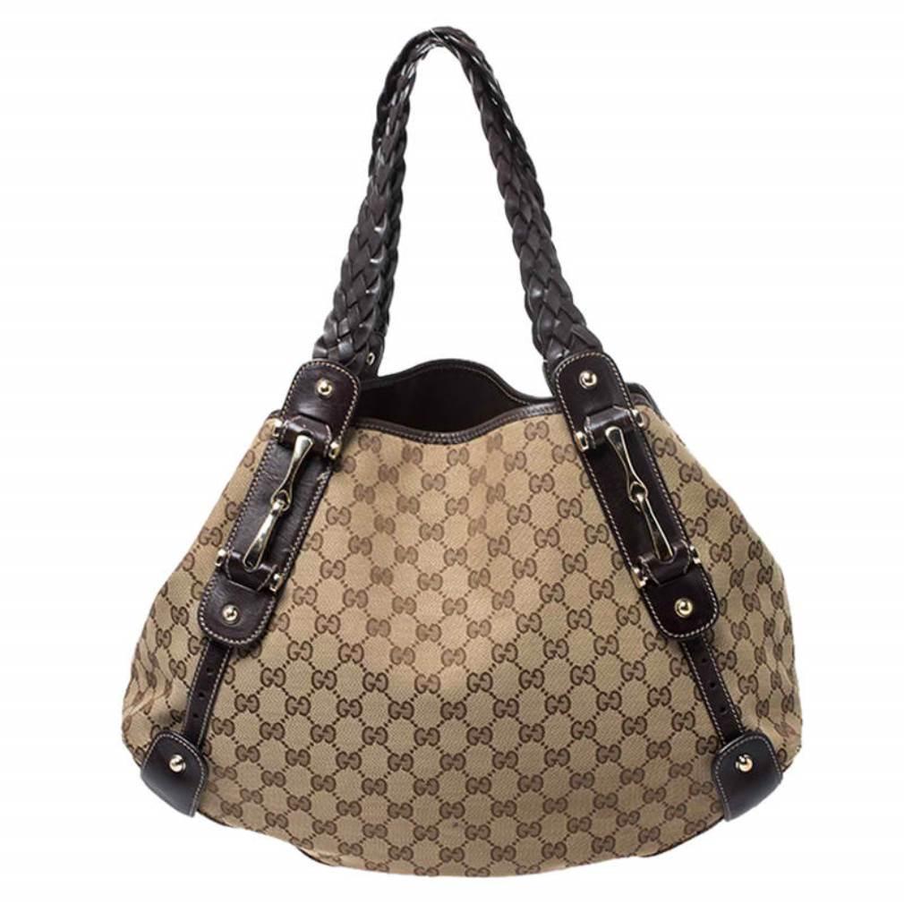 Take your style a notch higher with this Pelham shoulder bag from Gucci. Cut out from the brand's signature GG canvas and leather, it comes in beige and brown hues. The bag features two braided leather handles, a spacious fabric interior, and