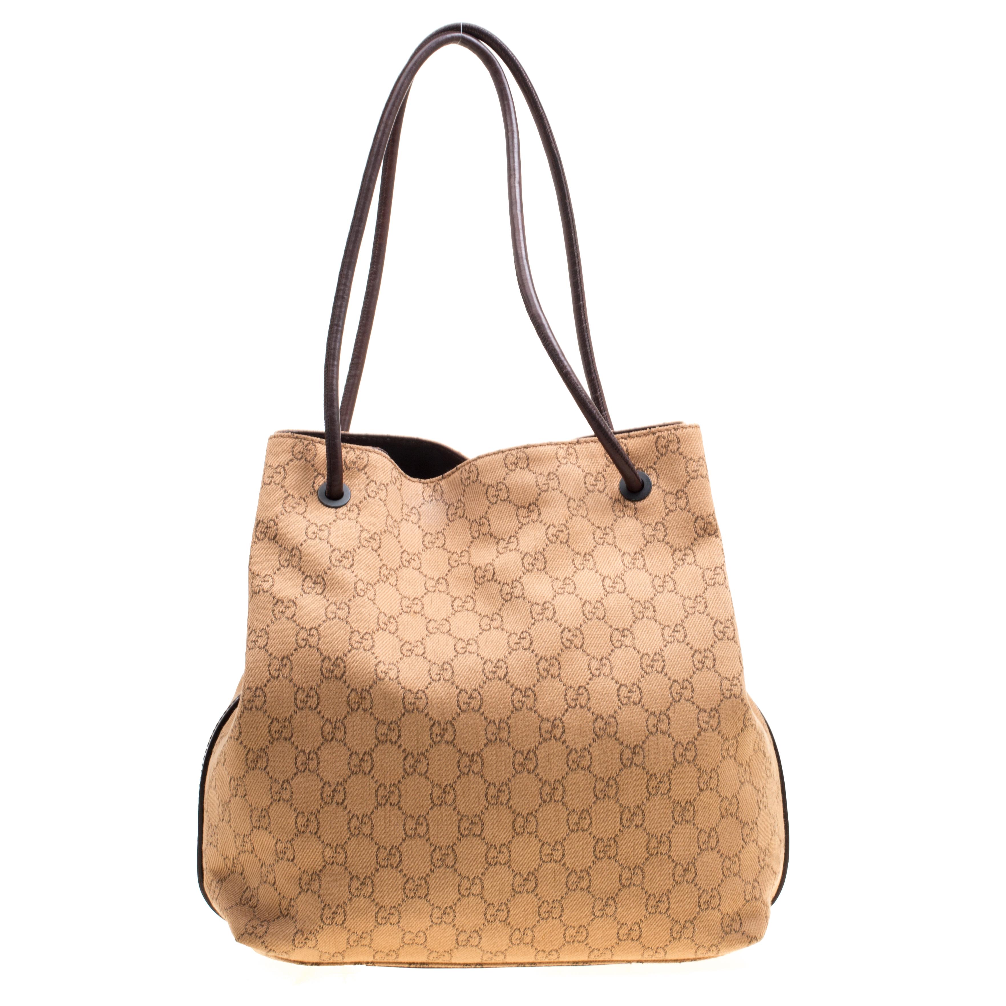 This unique Gucci tote is great for daily use. Crafted from monogram Gucci canvas along with leather trims, this bag is accented with leather handles that are attached to the bag with leather eyelets. Its interior is lined with brown fabric and