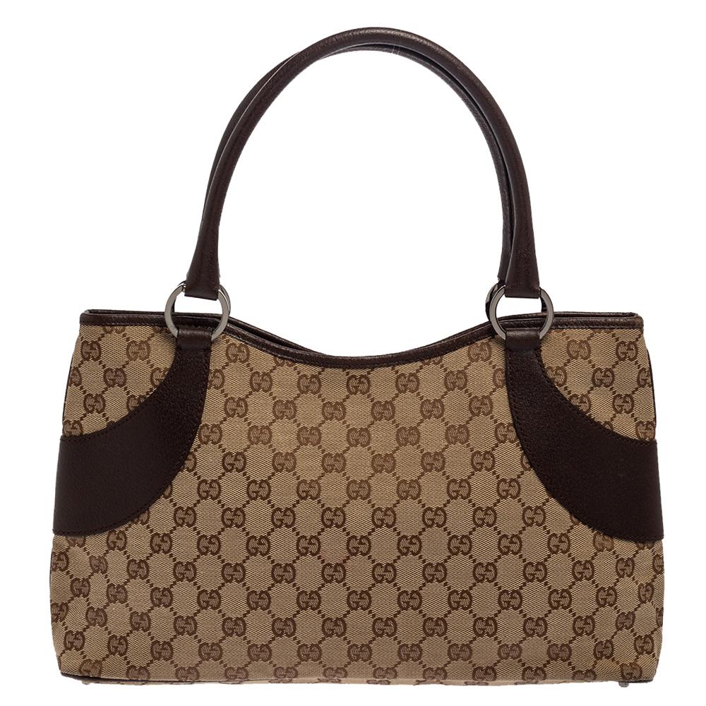 When practicability oozes out loads of style, you know it is the work of Gucci. Crafted from signature GG coated canvas and leather, this brown & beige tote features two top handles and leather trims. Styled with dual handles, the bag has a