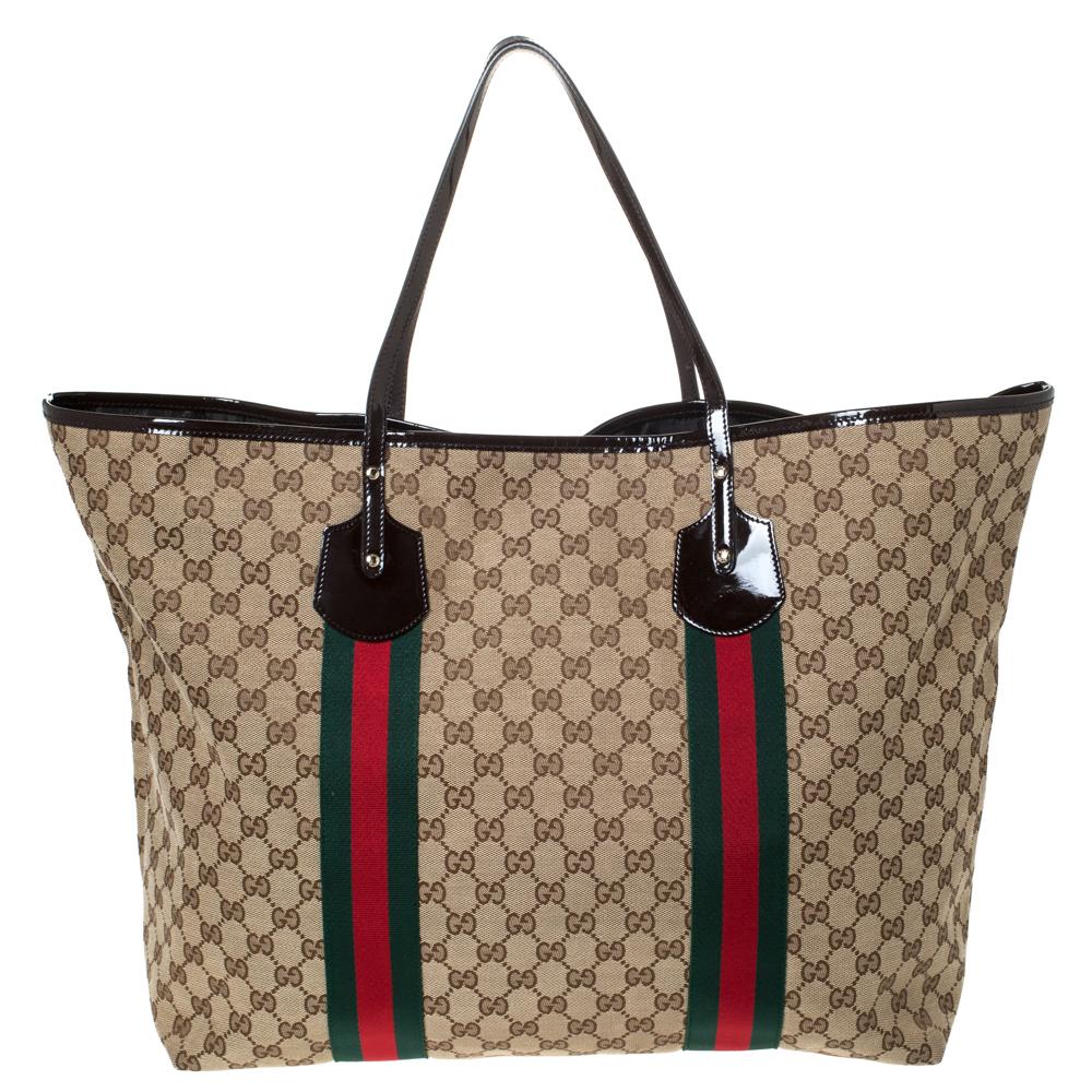 Crafted from monogram GG canvas, this tote by Gucci is of a perfect size. Its beige exterior is coupled with the signature Web stripe, patent leather trim, double handles and Gucci charms. Lined with nylon, the open interior includes one zipped
