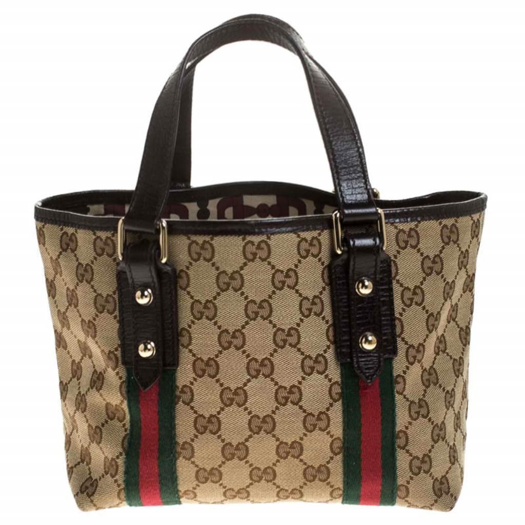 Flaunt your chic style with this mini Jolicoeur web tote from Gucci! Coated in GG canvas, the bag is accented with signature web trims, dual top handles, and gold-tone charms. It has a fabric-lined interior, equipped with a spacious compartment to