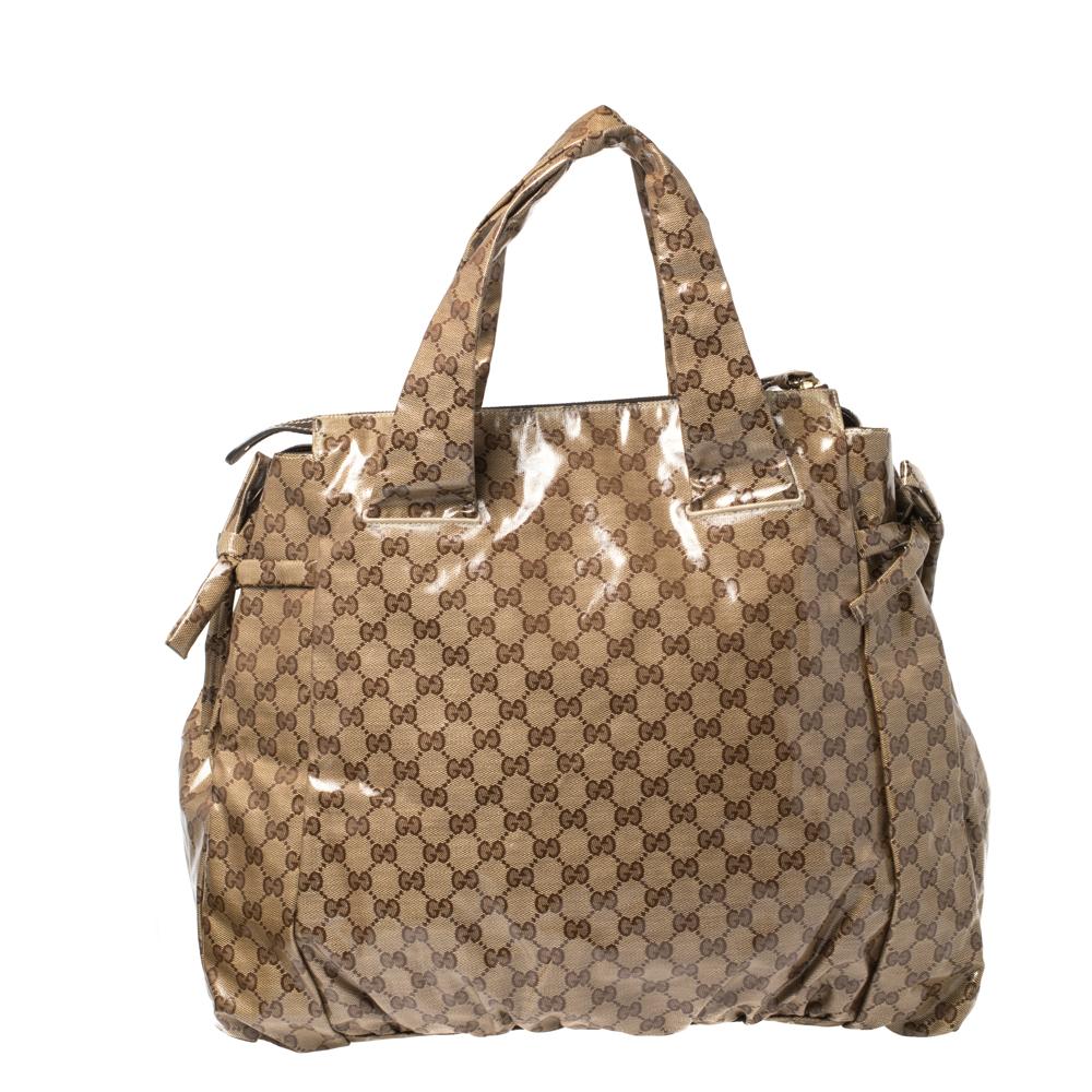This Gucci tote is stylish and built for everyday use. Crafted in Italy, it is made from GG crystal canvas and comes in a beige and brown hue. It has ties on the sides and dual handles for you to parade it. The nylon interior is spacious and is