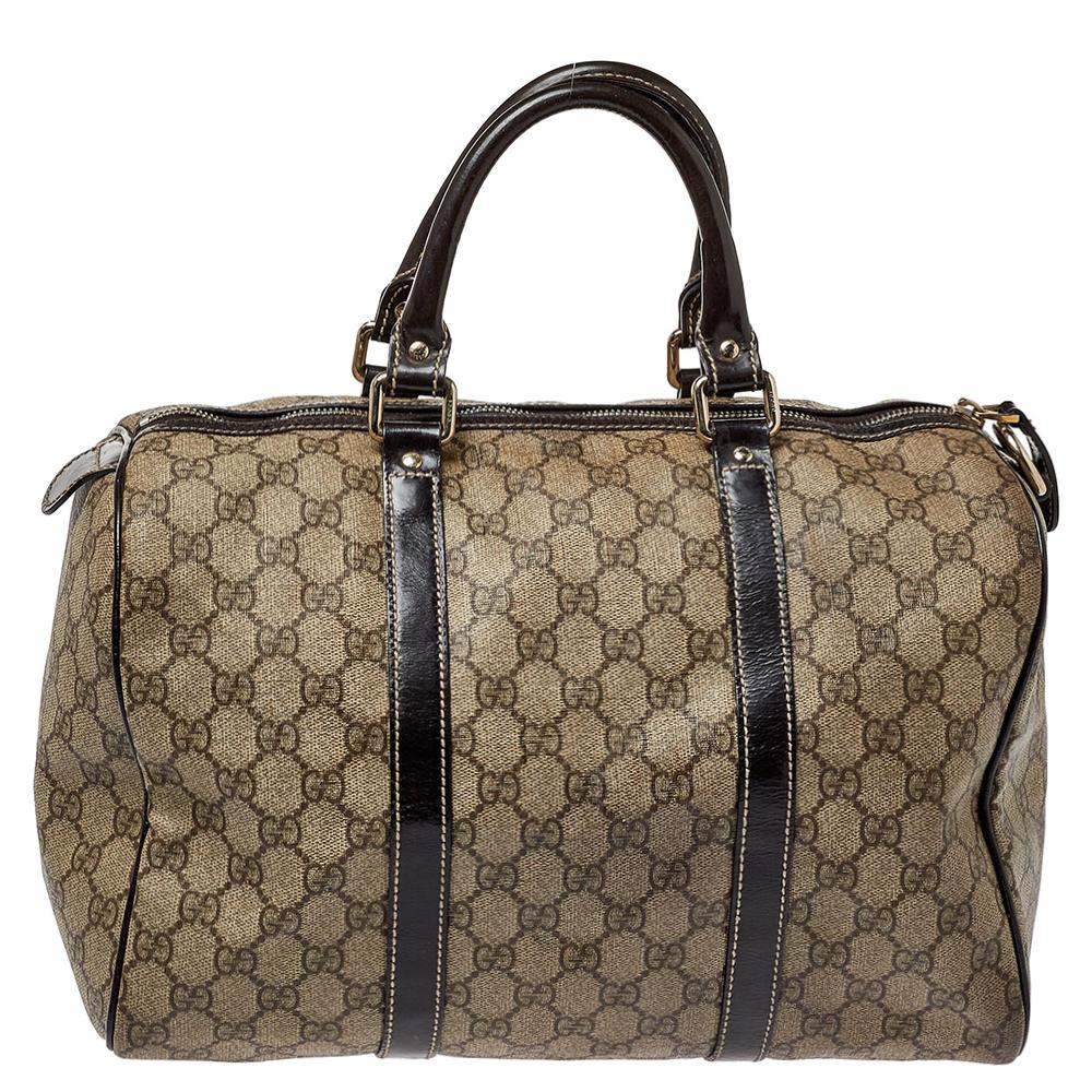 This Joy Boston bag blends Gucci’s timeless and iconic style. This creation is made from SS Supreme canvas and patent leather in beige and brown colors that exude a classy appeal. It comes with double handles and a top zip closure. The interior is