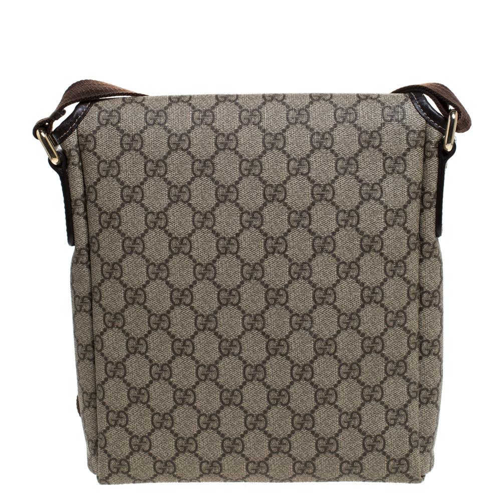 This stunning messenger bag from th house of Gucci is a classic that will never go out of style. Crafted from the brand's signature GG Supreme canvas and leather, it comes in beige and brown hues. It has a front flap that opens to a canvas interior