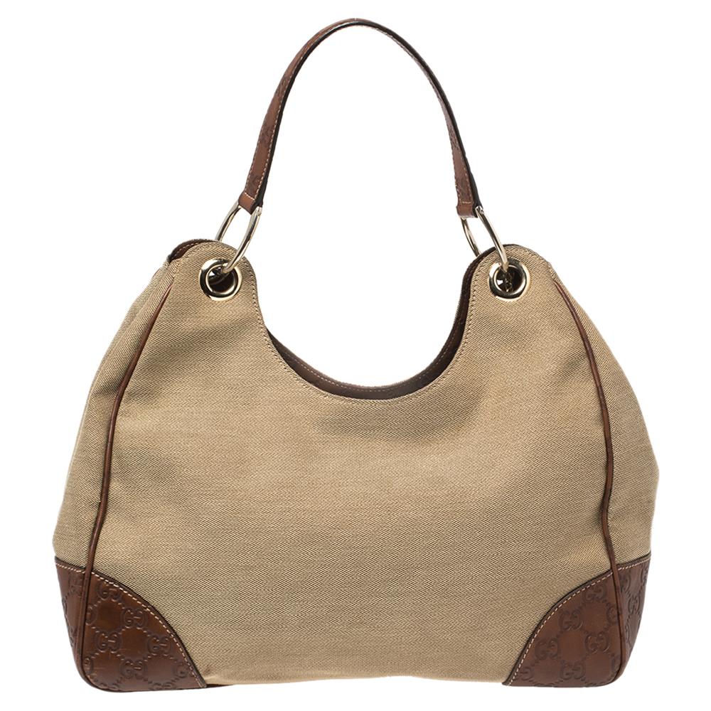 Realizzata con un'elegante forma a trapezio, questa hobo Guccisima di Gucci presenta un corpo beige e marrone in tela e pelle Guccissima. La borsa hobo è pratica in quanto offre ampio spazio per i tuoi oggetti essenziali. È dotata di interni