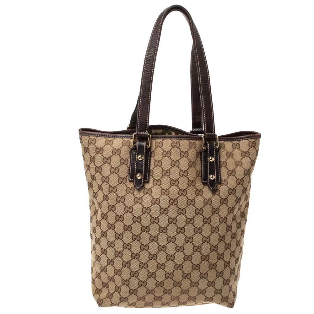 Crafted from monogram GG canvas, this tote by Gucci is of a perfect size. Its beige exterior is coupled with a mushroom embroidery as well as a charm on the front and double leather handles. Lined with canvas, the open interior includes one zipped