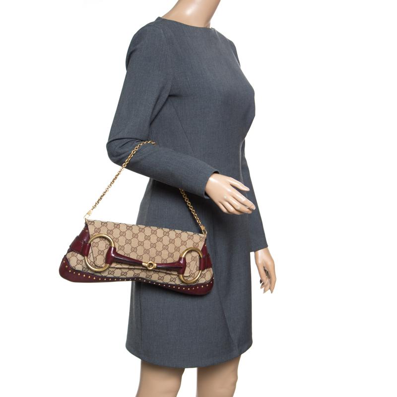 Trendy, stylish and very classy, this beige and burgundy clutch from Gucci will make you fall in love with it! It is crafted from the signature GG canvas and leather and features a front flap with a large horsebit buckle closure. Small gold-tone