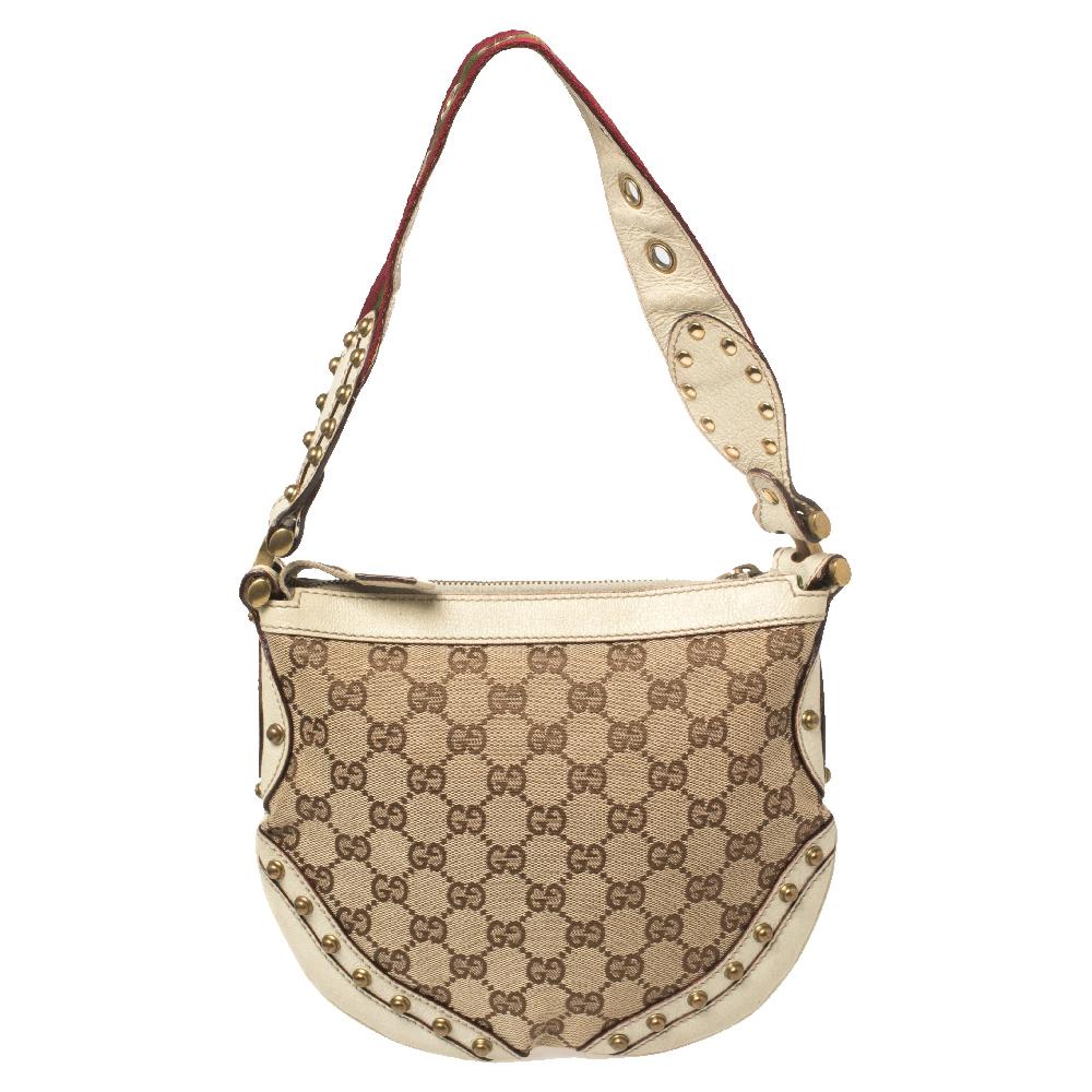 Take your style a notch higher with this Pelham hobo from Gucci. Cut out from beige & cream GG canvas & leather, the stunning hobo bag features a web handle with grommets, stud detailing, a spacious fabric interior and gold-tone hardware. This hobo