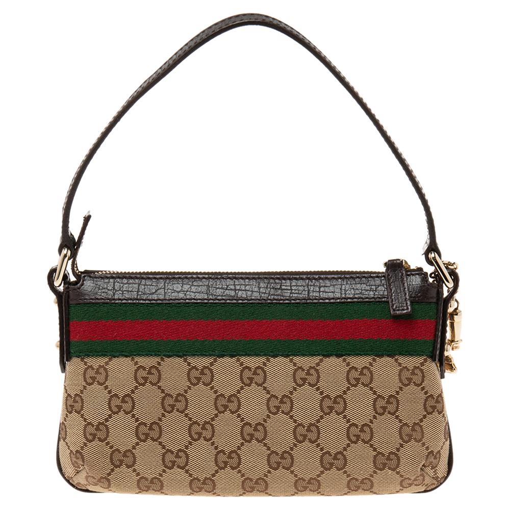 This Pochette clutch bag from the House of Gucci is truly the epitome of skill and excellence. It is made from dark brown, beige GG canvas and leather, with the iconic Web Stripe outlining its shape. It has a single handle, a neat fabric-lined