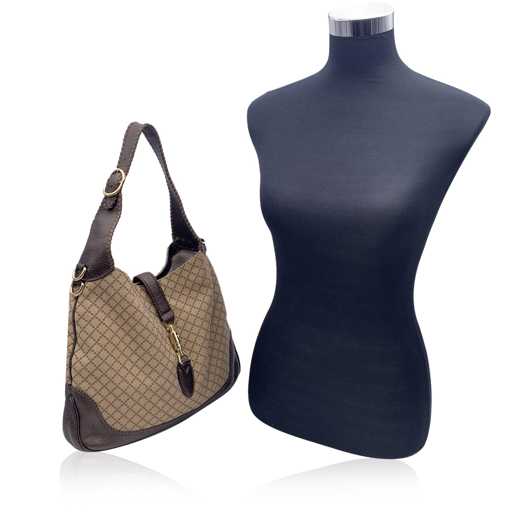 Magnifique sac hobo 'New Jackie' de Gucci. Le sac est réalisé en toile diamantée beige avec une bordure et une bandoulière en cuir marron. Fermeture classique 