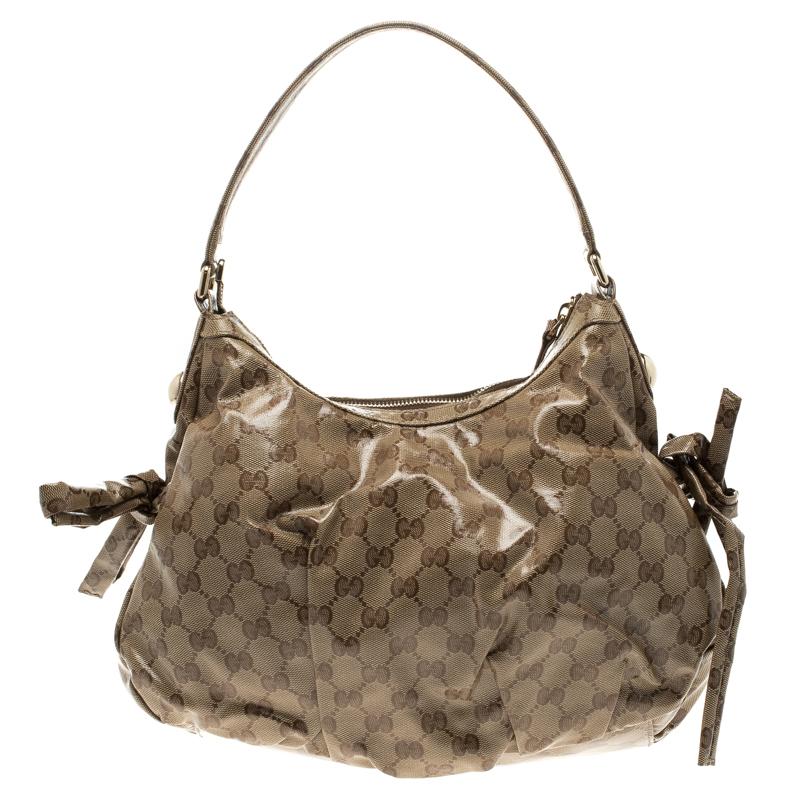 Fashioned in a beige and ebony coated canvas, this Gucci Hobo features the 'GG' web detailing on the outer body. Detailed with pleats, this bag comes with tie-up closure on the sides and fitted with a slim top handle. The fabric lined interior can