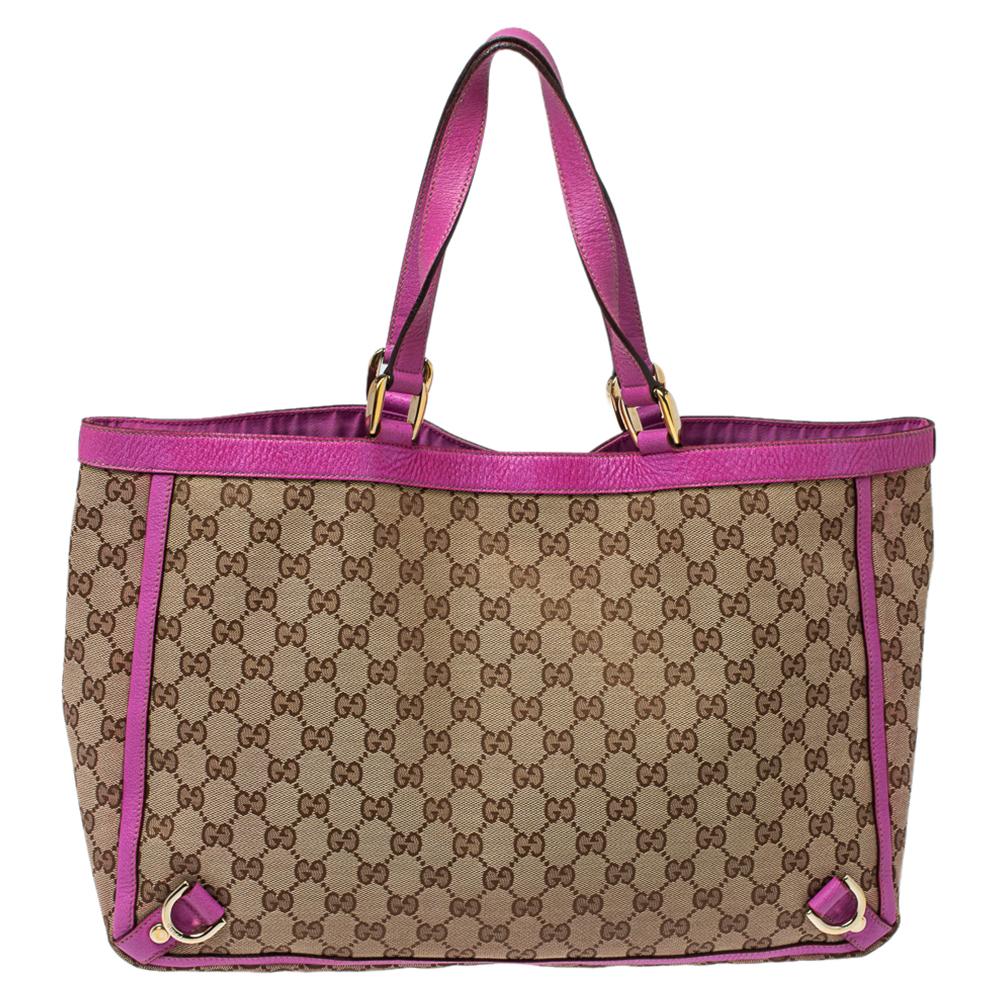Gucci's classic Abbey D-Ring tote is a timeless accessory. Made in Italy, this beige creation is crafted from GG canvas and features fuchsia leather trims and handles. It opens to a fabric-lined interior with enough space to hold all your daily