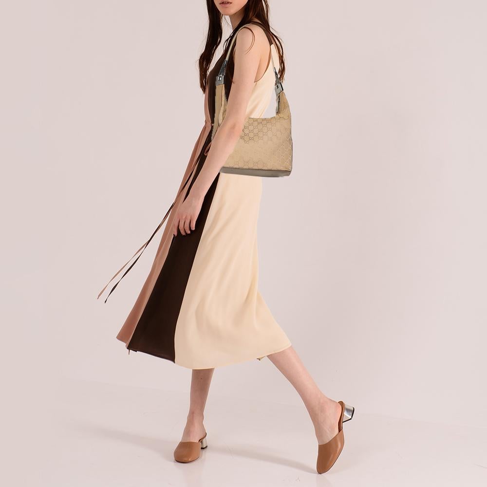 This Gucci shoulder bag will complete all your casual ensembles. The stylish exterior is made from beige GG monogram canvas that is accented with leather trims. The fabric-lined interior opens up with a zip closure and features a zip pocket.

