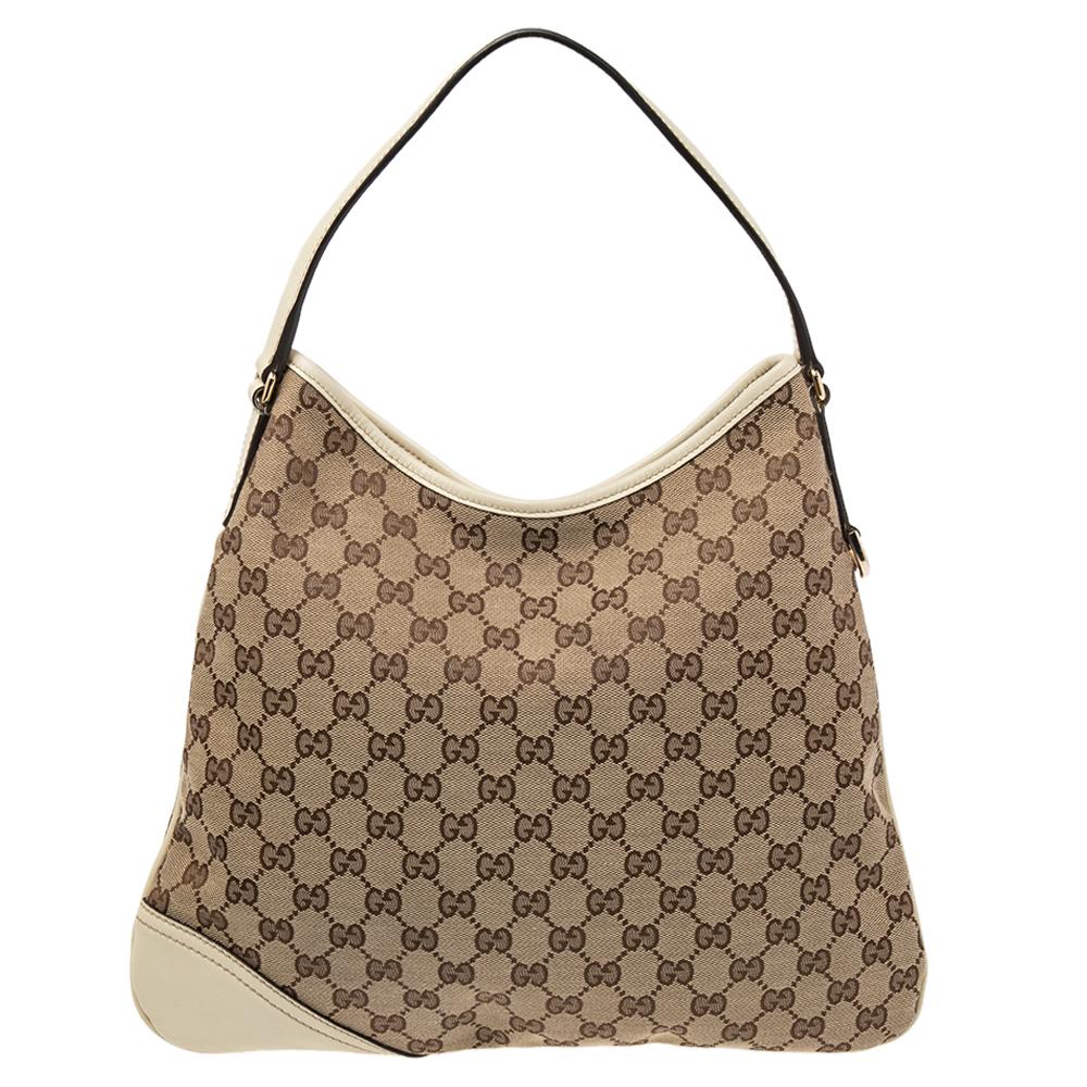 Keep your day look refined and casual with this New Britt hobo by Gucci. Made from black GG monogram canvas and leather, it is accented with a gold-tone GG logo at the corner. It comes with a single shoulder strap and a magnetic snap closure. The